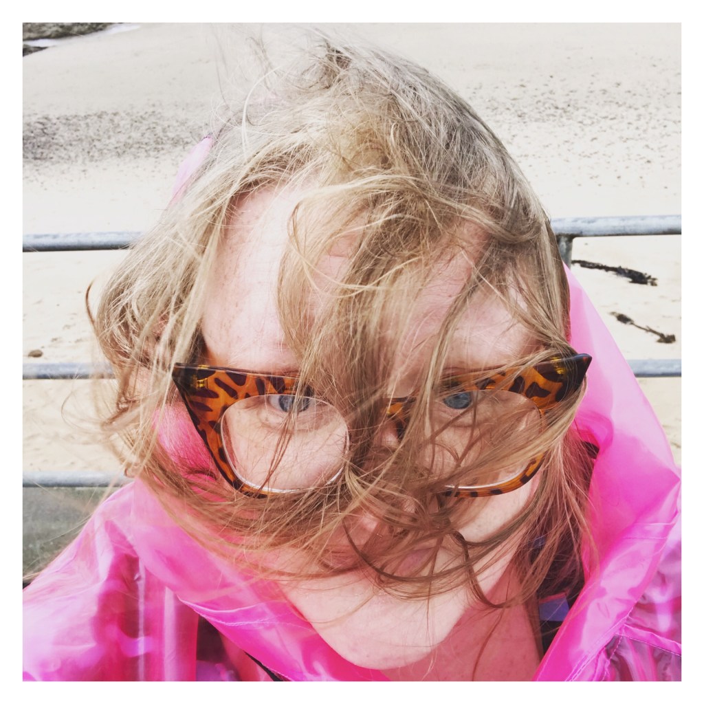 ly in pink anorak with windswept hair in her face 