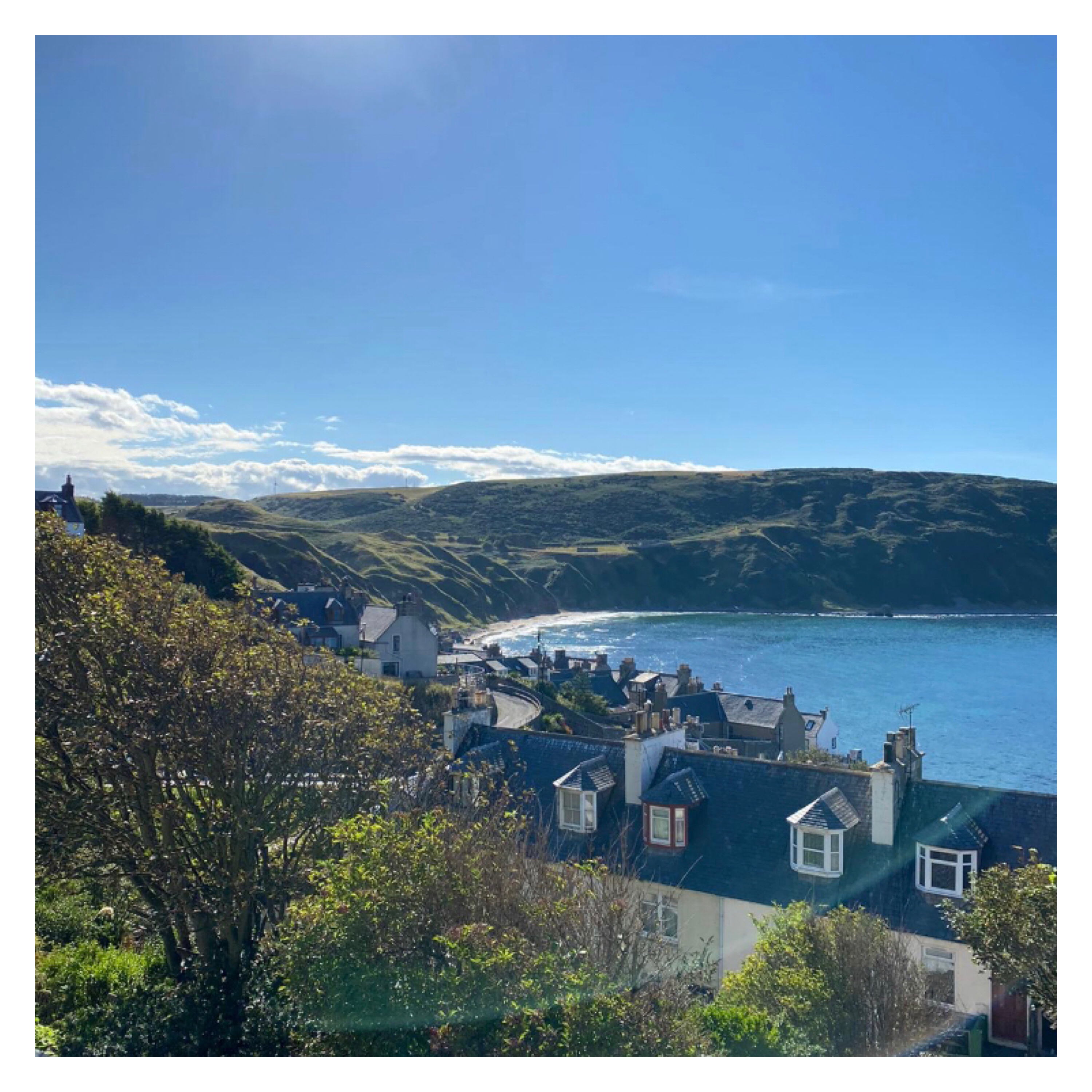 Cove beach surrounded by cliffs and cottages on hill 