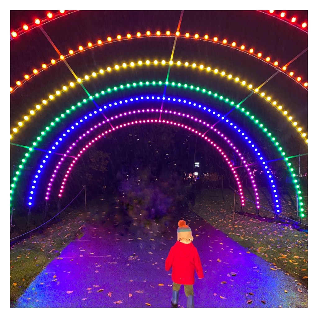 Toddler running under neon rainbow 