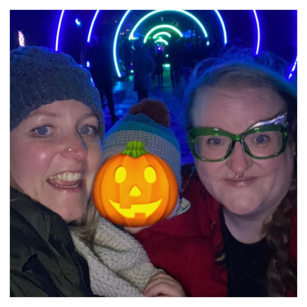 Two adult smiling women and toddler surrounded by lights 