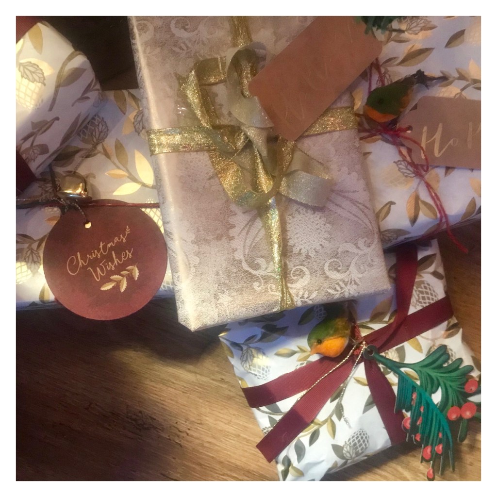 Xmas presents wrapped in white & good paper with red ribbons & tiny robin red breast decorations
