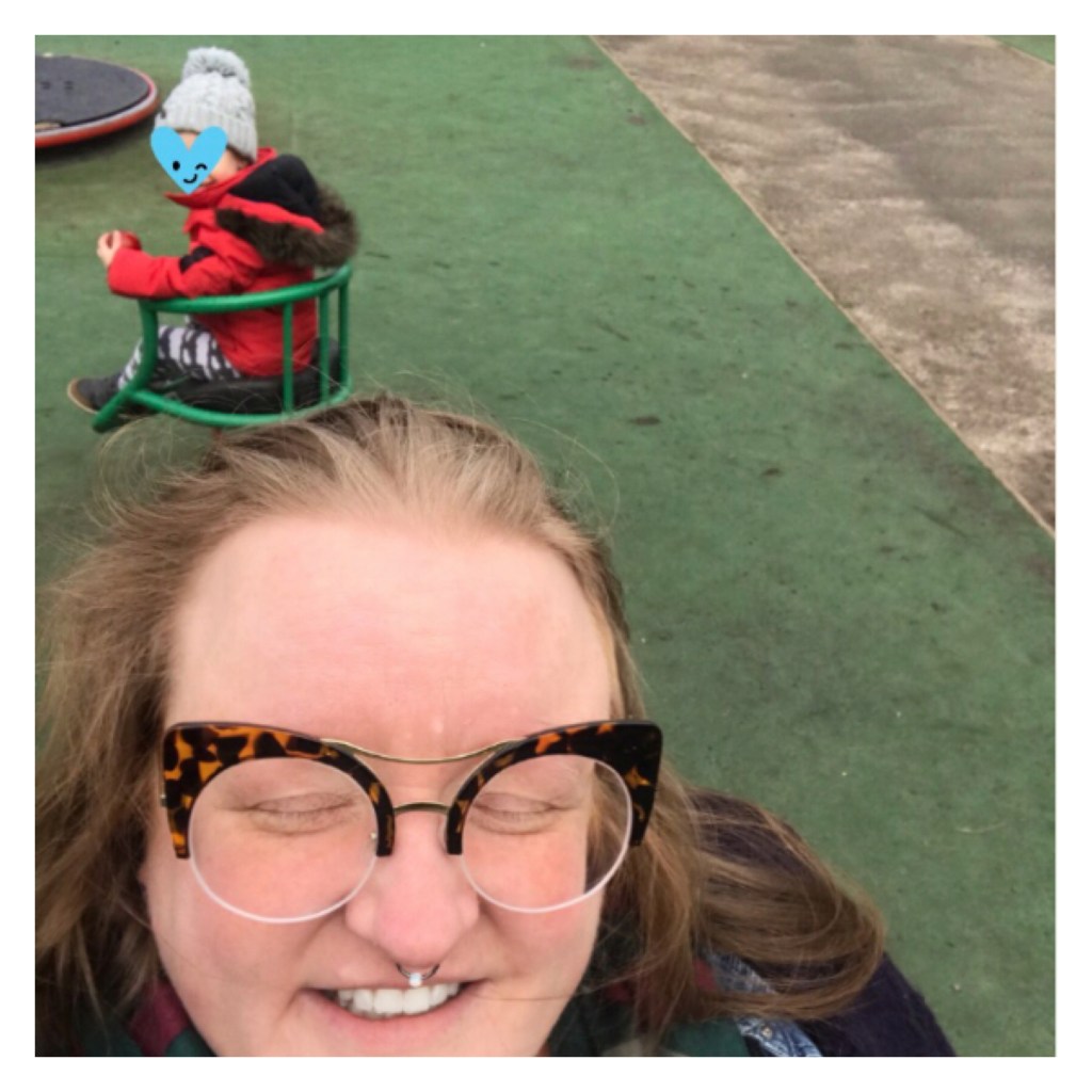 ly is laughing in a swing park with her nephew behind her