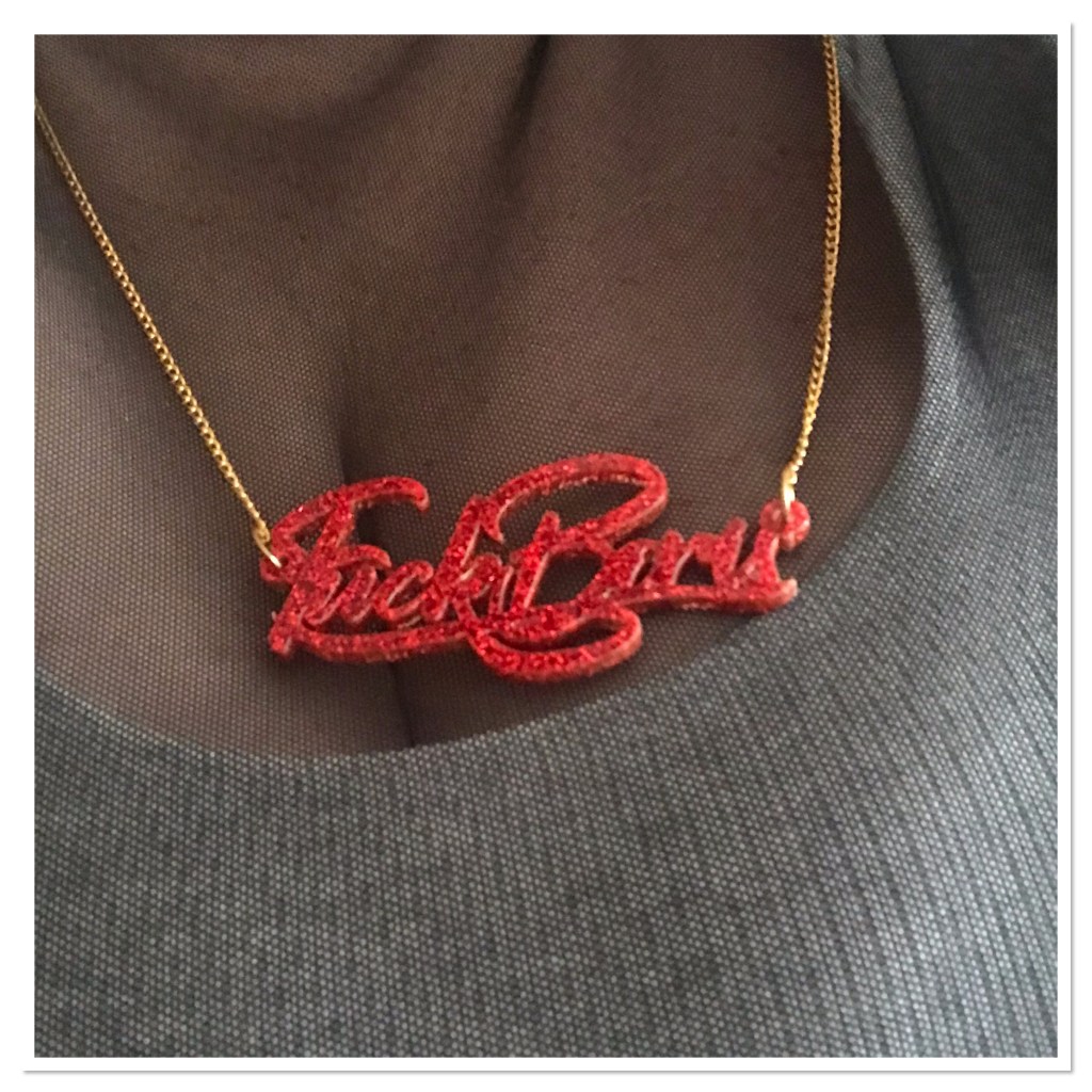 Red glitter text necklace  spelling ‘fuck Boris’ 