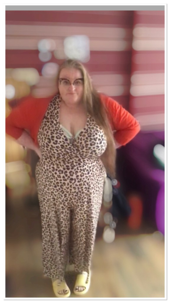 Ly is standing with blurred background wearing leopard print jumpsuit 