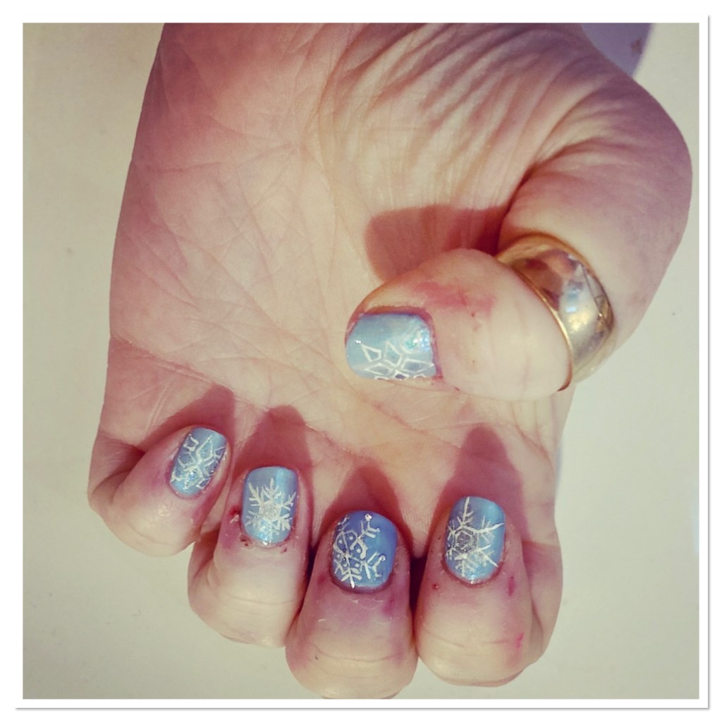 Pale blue manicure with the white sparkly snow flakes design 