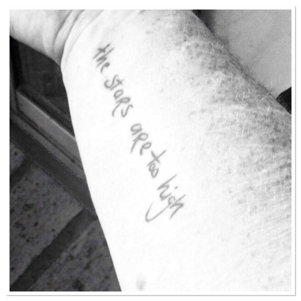 The words ‘ the stars are too high’ tattooed on freckled arm