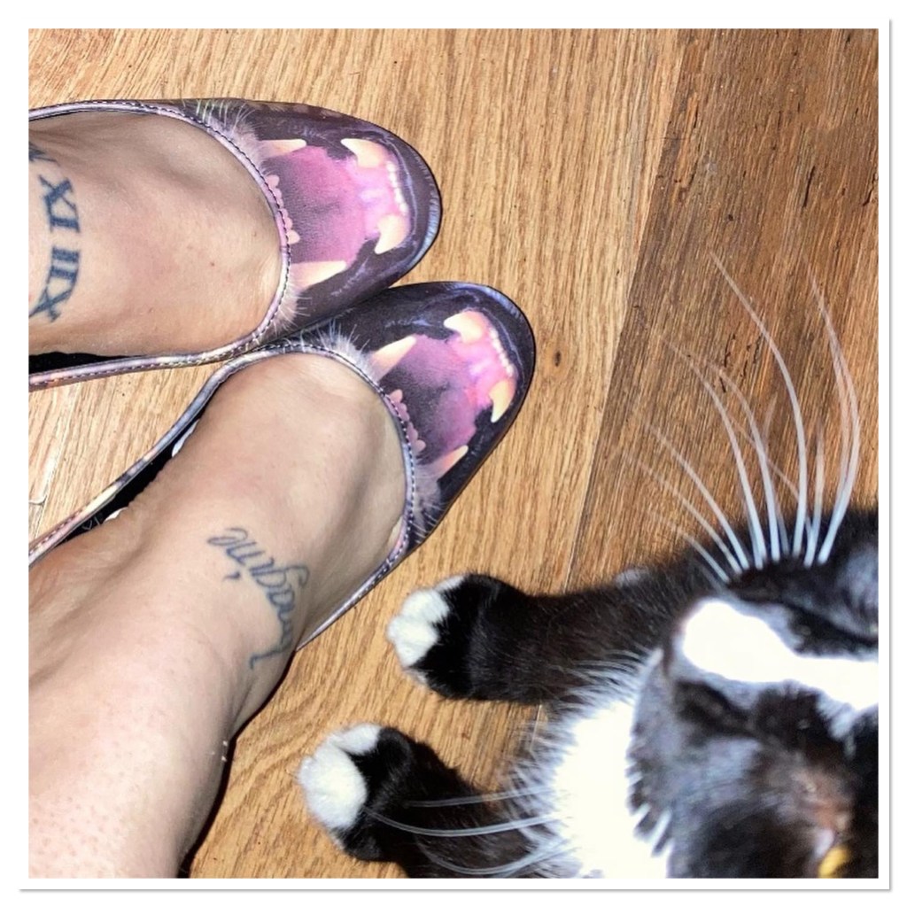 Tattooed pale white feet in shoes with Leopard fangs and black cat 