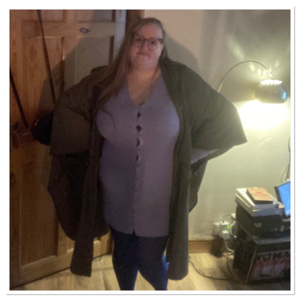 Fat white women with hands on her hips wearing blue jumper dress& khaki rain mac