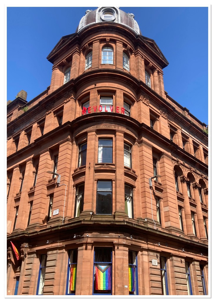 Red Sandstone building with domed roof and pride flags in windows. 